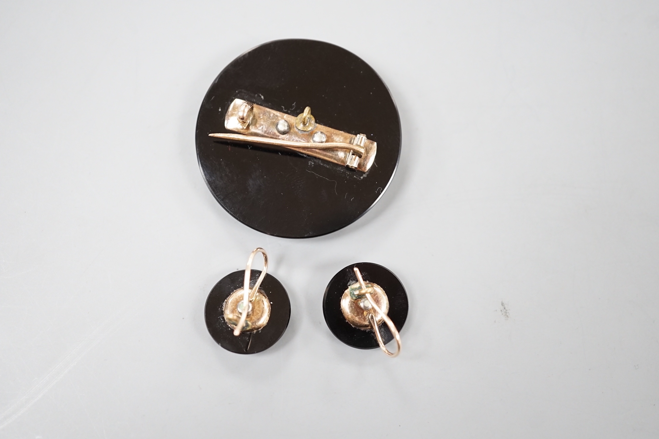 A late Victorian suite of yellow metal mounted black onyx and seed pearl mourning jewellery, coimprising a brooch, 33mm and pair of earrings.